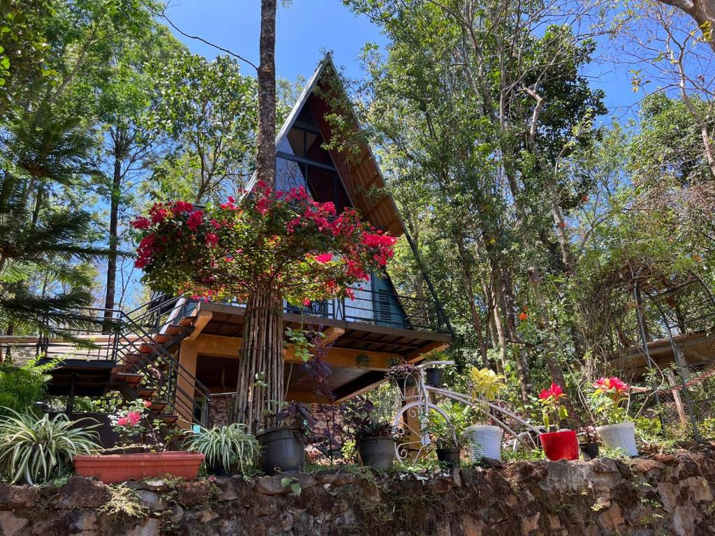 una casa en el árbol con flores delante en Wild root stay- Orchid Chalet en Vythiri