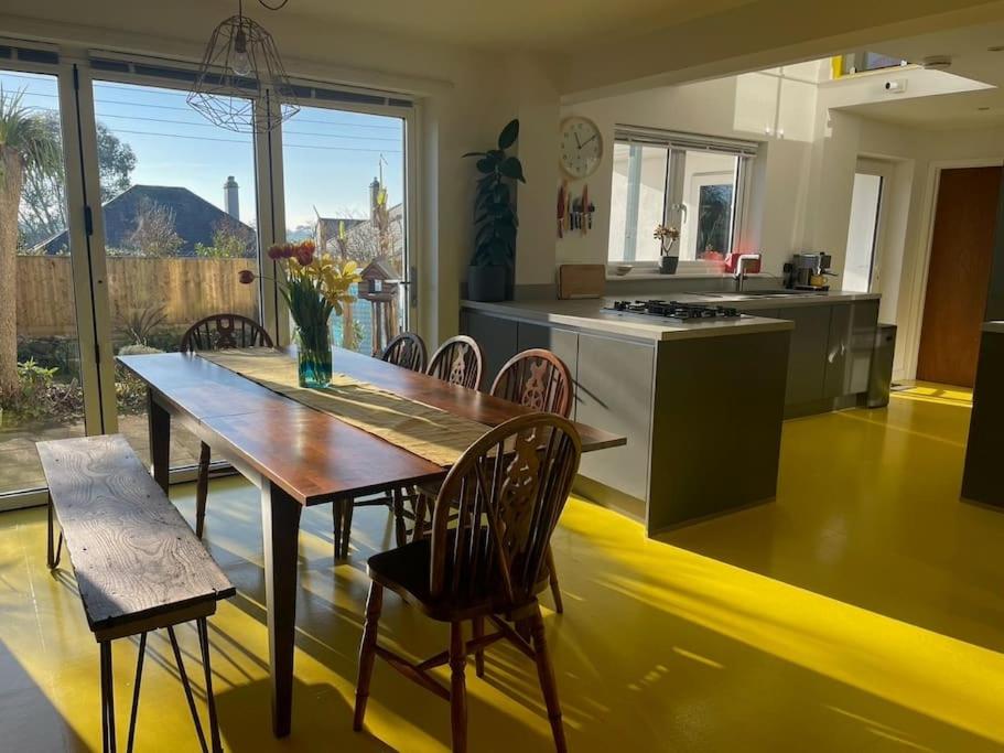 a kitchen with a wooden table and chairs in a kitchen at Stunning, Modern and Spacious House - Truro in Truro