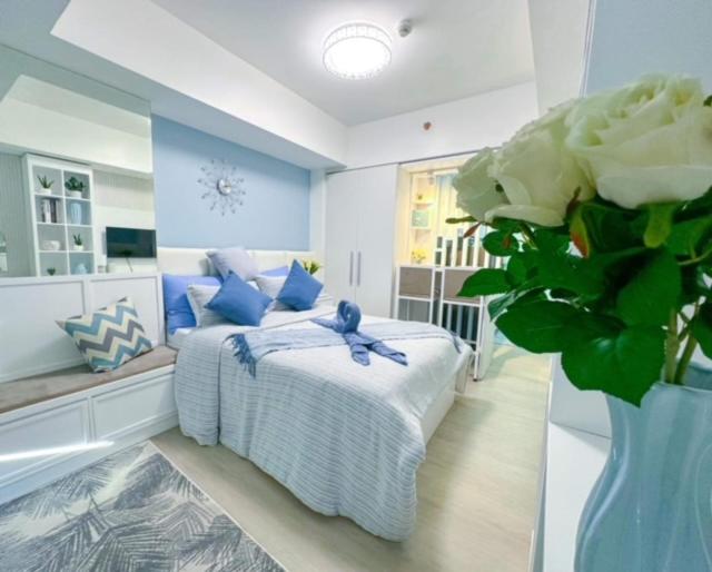 Un dormitorio azul y blanco con una cama y un jarrón de flores en LA CASA ALEYKA AZURE NORTH PAMPANGA BALI Tower 518, en San Fernando