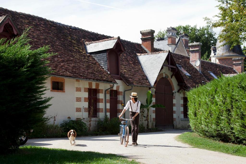 a man with a bike and a dog in front of a house at Cottages et B&B de Troussay in Cheverny
