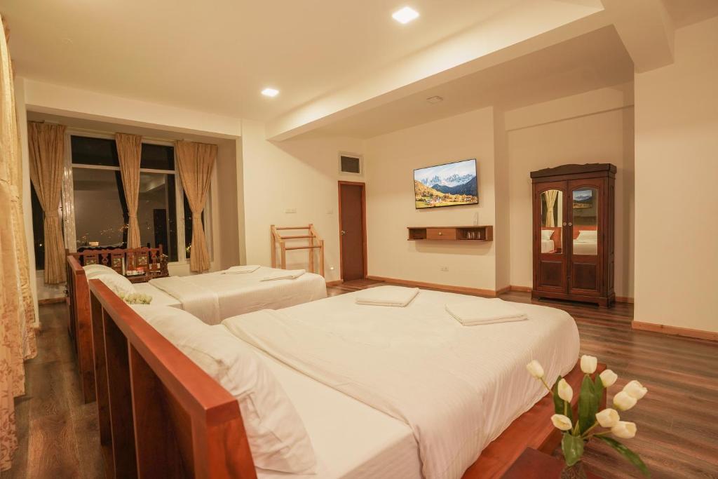 a hotel room with two beds and a television at Richfields in Ooty