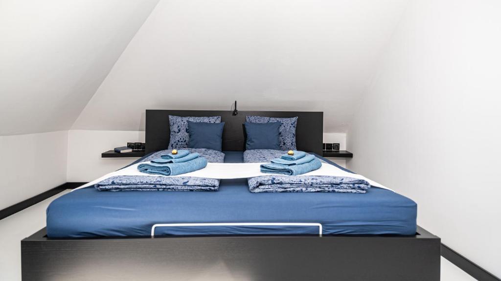 a large bed with blue sheets and blue pillows at Arácsi Apartman 1610 in Balatonfüred