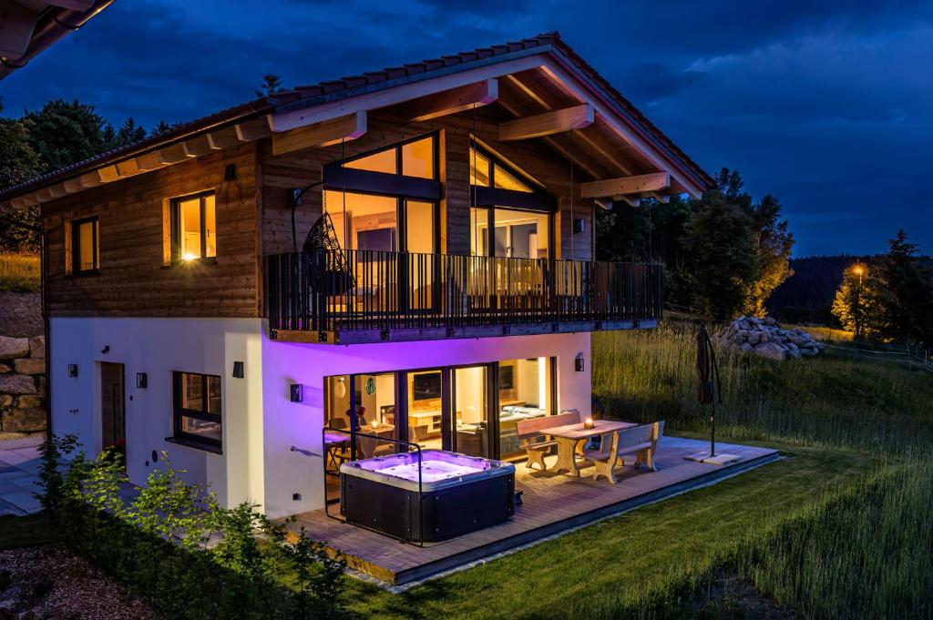 a house with a deck and a table in front of it at Kroner Chalets in Zwiesel