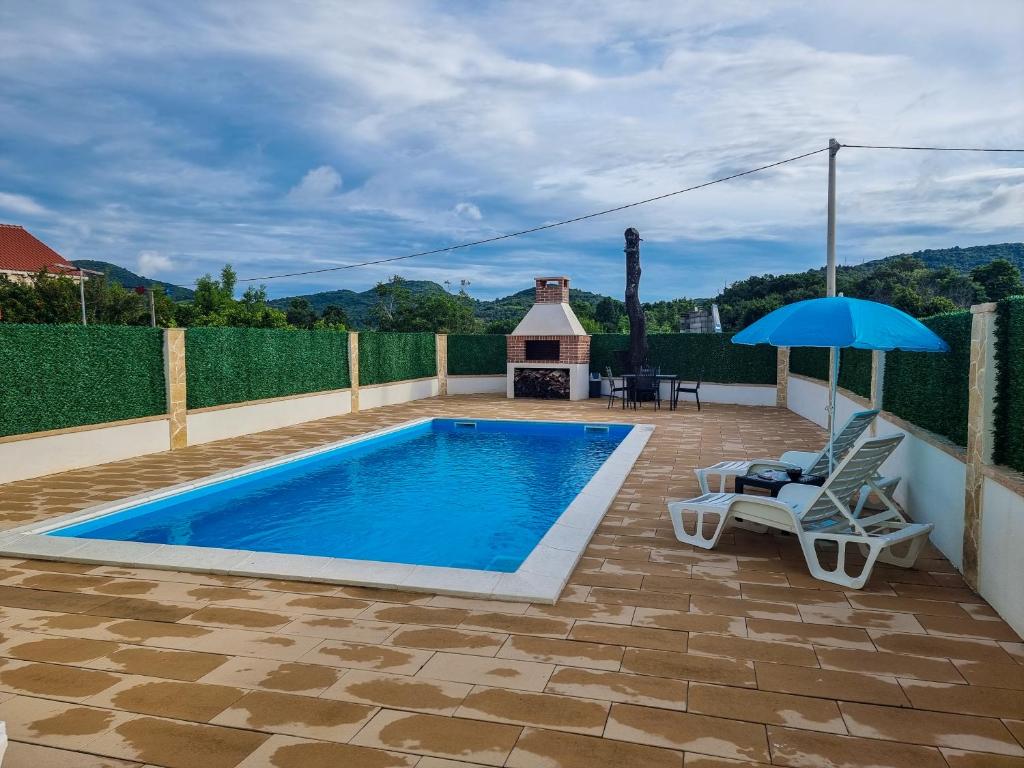 a pool with a chair and an umbrella on a patio at Villa Danijela in Janjina