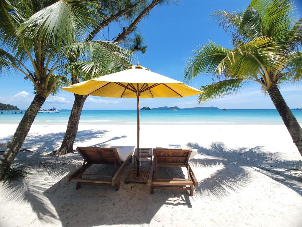 a table and chairs under an umbrella on a beach at Long Set Resort in Koh Rong Island