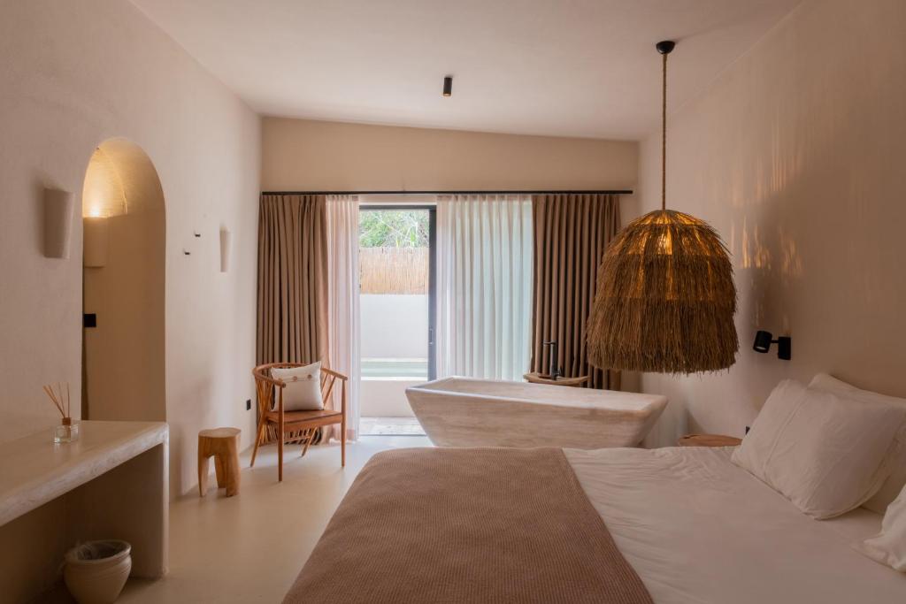 a bedroom with a bed and a chair and a tub at GAIA Alaçatı BY THE SEA - Adult Only in Cesme