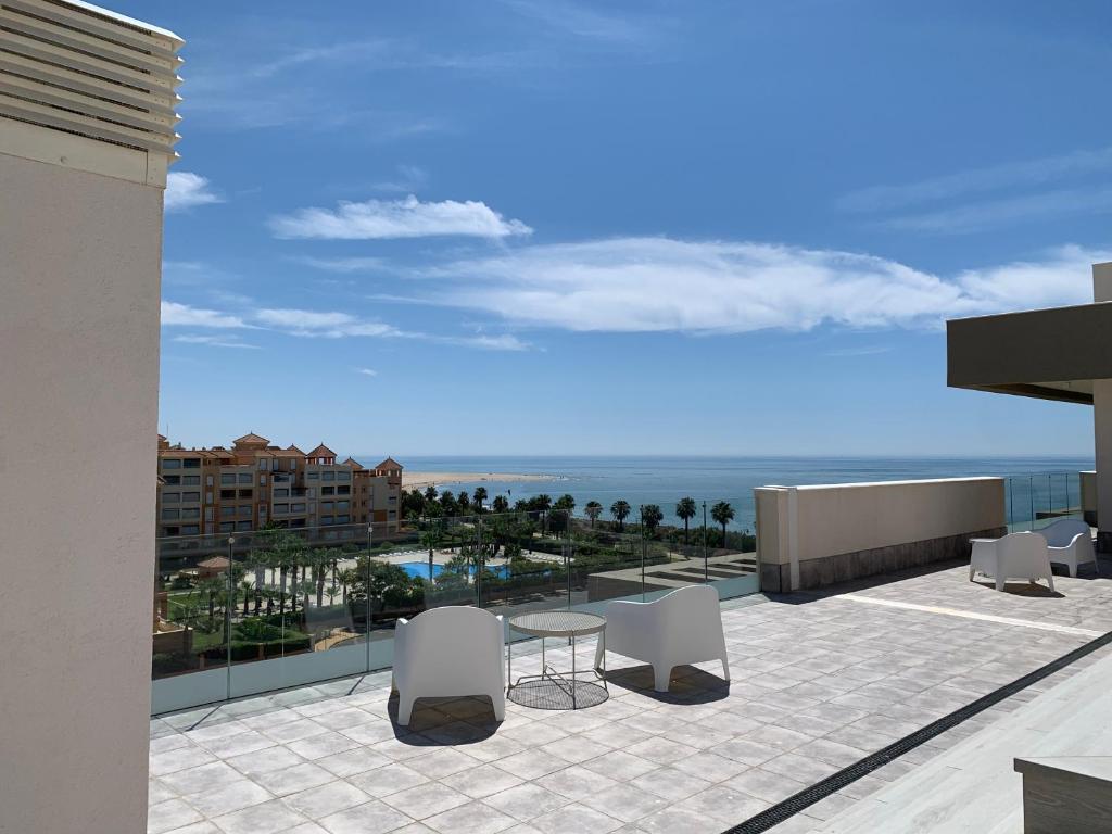 taras ze stołem i krzesłami na balkonie w obiekcie Penthouse with wide terrace next to the ocean w mieście Huelva