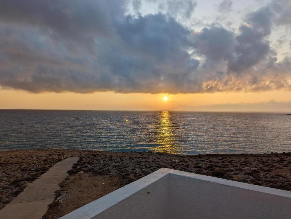 einen Sonnenuntergang über dem Meer mit einer Badewanne am Strand in der Unterkunft ARKASA KARPATHOS SEAFRONT PARADISOS in Karpathos