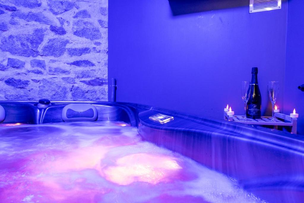 a hot tub in a room with a bottle of wine at Cosy Room Jacuzzi Romantique in Nantes
