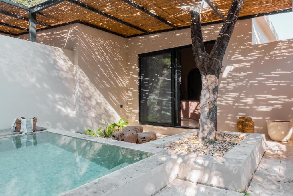 a house with a swimming pool and a tree at GAIA Alaçatı BY THE SEA - Adult Only in Çeşme