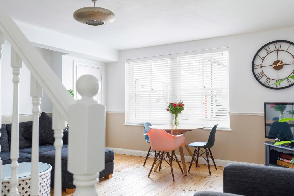 a living room with a table and chairs and a clock at Beachfront Getaway 2-Bedroom House with FREE Private Parking & Patio in Brighton & Hove