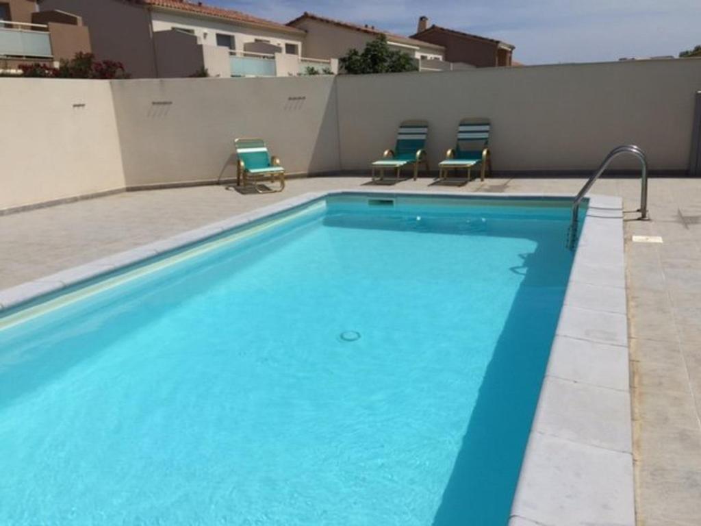 a swimming pool with two chairs next to a building at Villa Leucate, 4 pièces, 7 personnes - FR-1-81-578 in Leucate
