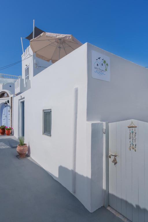 a white building with a door and an umbrella at Villa Paradeisos Karterados in Karterados