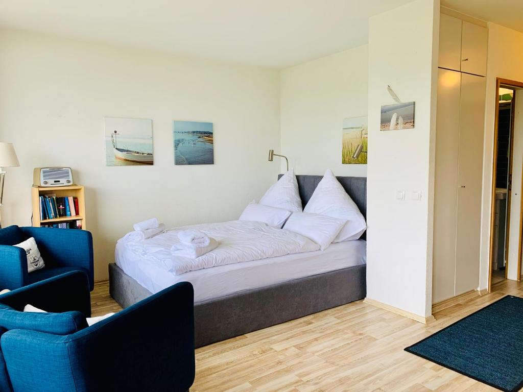 ein Schlafzimmer mit einem Bett und einem blauen Stuhl in der Unterkunft Ostseeschwalbe am Fahrenkrog in Sierksdorf