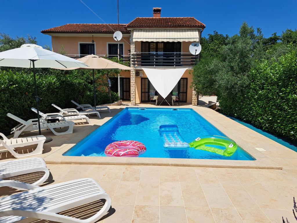 a swimming pool with chairs and a house at Spacious apartment in Pula for 6 persons and with a big swimming pool in Pula