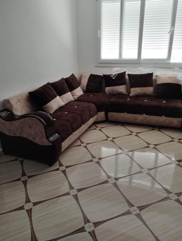 um sofá castanho num quarto com piso em Residence Tazoumbirt em Tigzirt