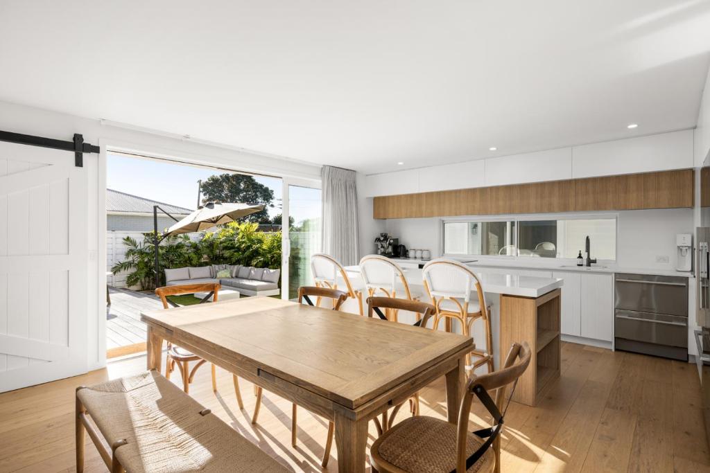 a kitchen and living room with a wooden table and chairs at Seas the Day Comfort and Spa in Mount Maunganui