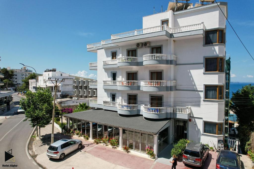 un edificio blanco con coches estacionados frente a él en Hotel Alpha, en Sarandë