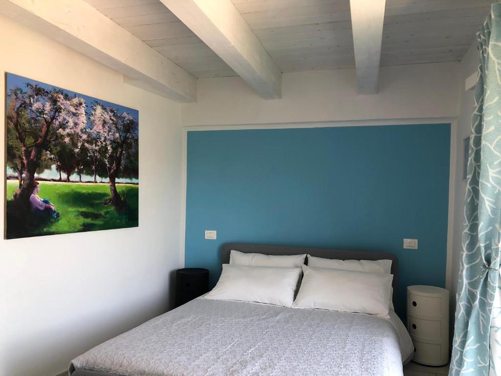 Un Capriccio - Ginepro في Aieta: غرفة نوم بسرير مع لوحة على الحائط