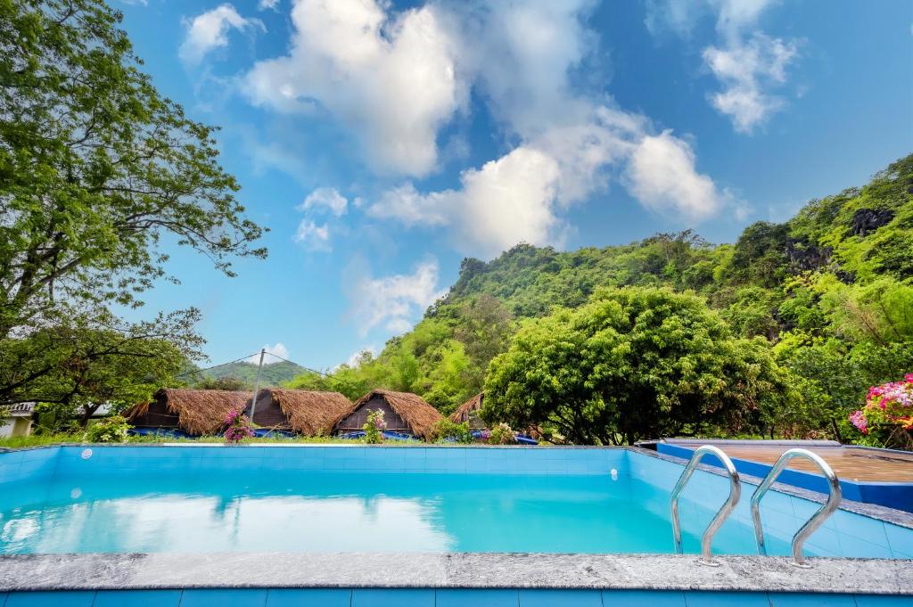a swimming pool with mountains in the background at Catba Papillon Garden Bungalows & Resort in Cat Ba