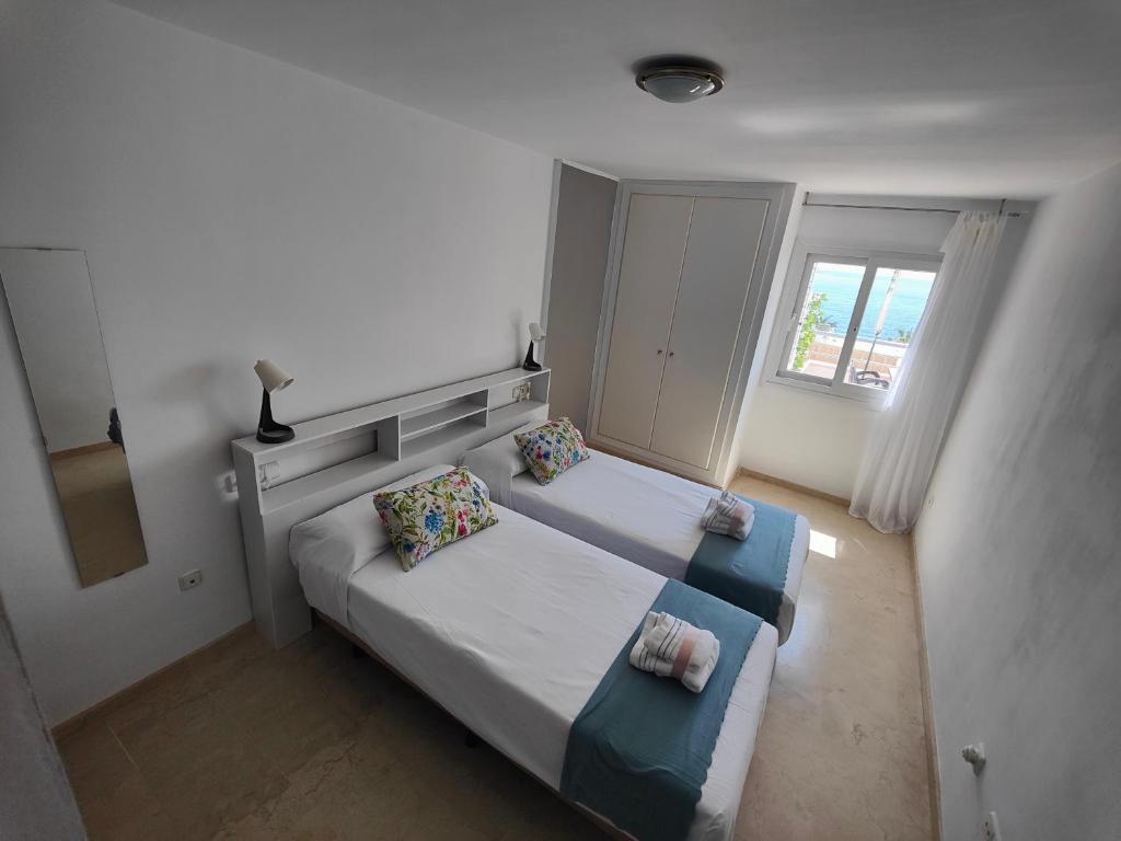 Habitación pequeña con 2 camas y ventana en Apartamento Playa del Faro en Garrucha