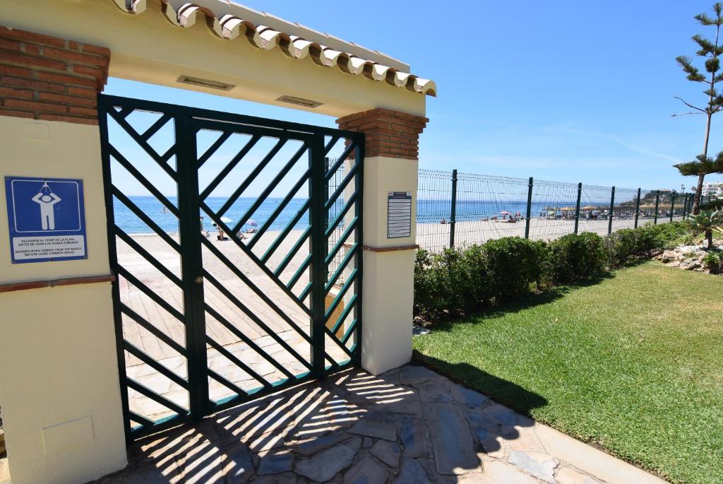 ein Tor zu einem Haus mit Strand im Hintergrund in der Unterkunft Las Mimosas in La Cala de Mijas