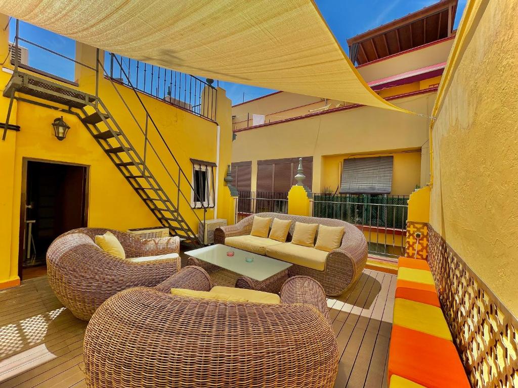 eine Terrasse mit Korbstühlen, einem Sofa und einem Tisch in der Unterkunft House -Rooftop&Jacuzzi -StayInSeville in Sevilla