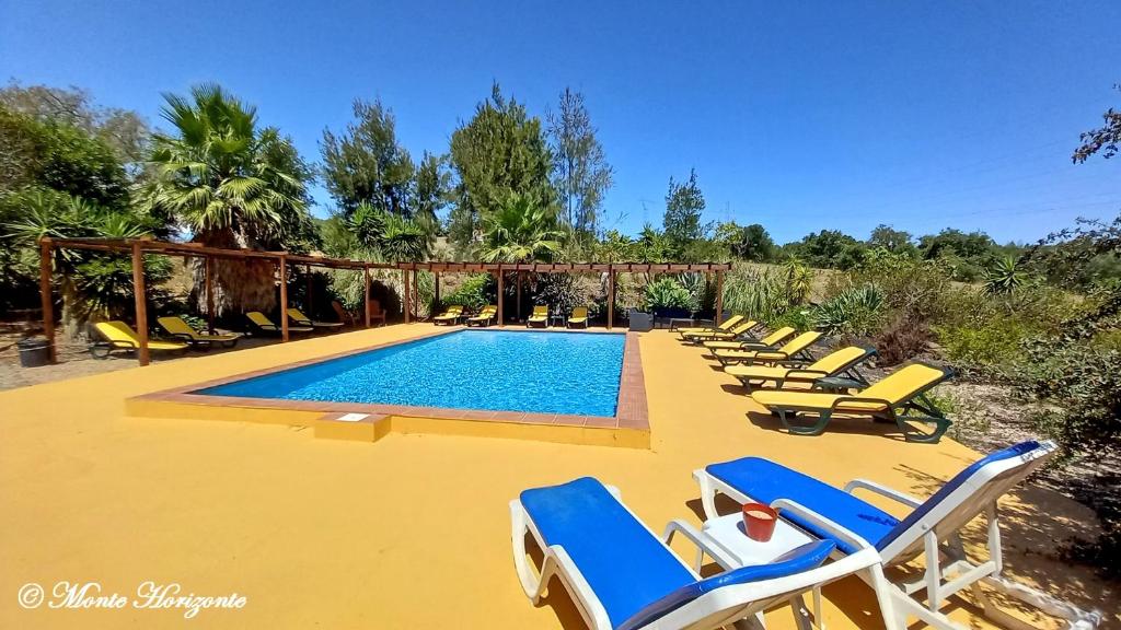 a group of lounge chairs and a swimming pool at Monte Horizonte - The Private Villas - Turismo Rural - Eco & Nature in Santiago do Cacém