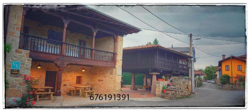 a building with a balcony and a table in front of it at Los Campos Vivienda Vacacional in Cangas de Onís