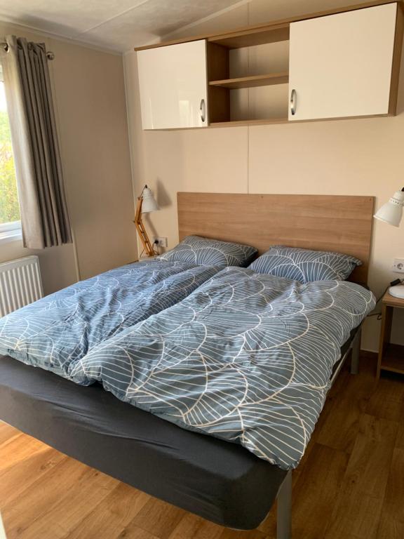 ein Bett mit blauer Decke in einem Schlafzimmer in der Unterkunft Chalet Rivendell in Menaldum