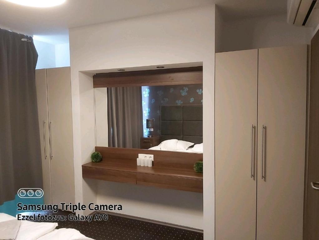 ein Schlafzimmer mit einem Spiegel an der Wand in der Unterkunft Plage apartman in Hajdúszoboszló