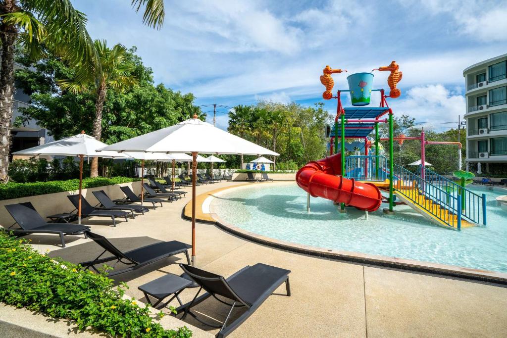 a pool with a slide in the water with chairs at Wyndham La Vita Rawai Phuket in Rawai Beach