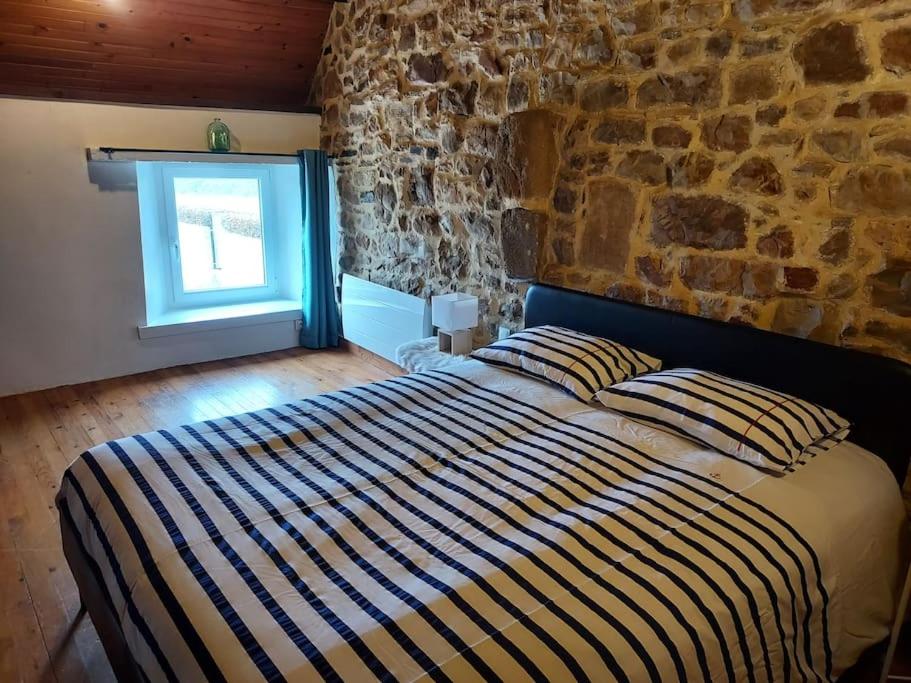 Bett in einem Zimmer mit einer Steinmauer in der Unterkunft SCIOTOT-BORD DE MER - LA GRANGE in Les Pieux