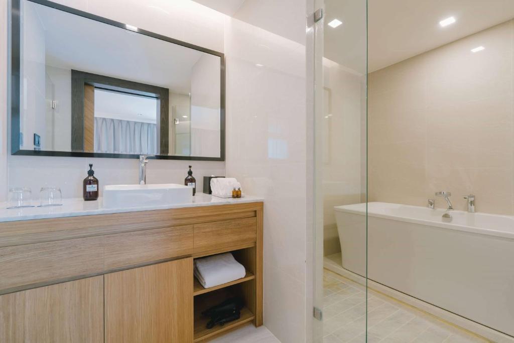 a bathroom with a sink and a tub and a mirror at Wyndham La Vita Rawai Phuket in Rawai Beach
