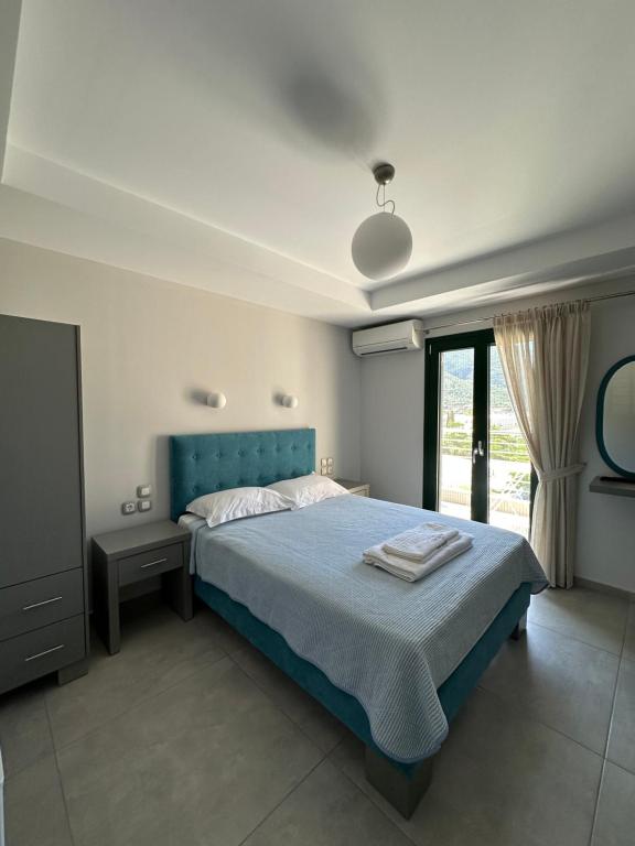 a bedroom with a blue bed and a window at Hotel Odyssion in Vasiliki