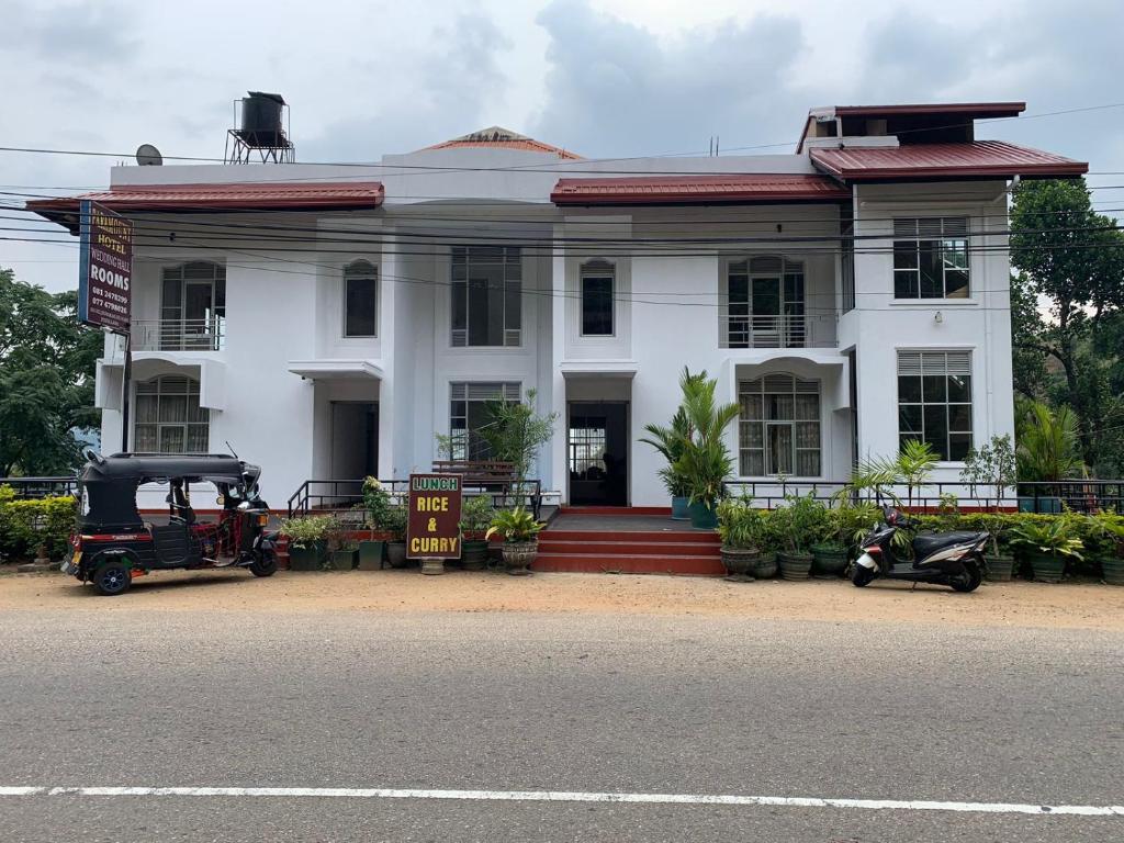 a white house with motorcycles parked in front of it at Paramount Hotel Pussellawa in Pussellawa