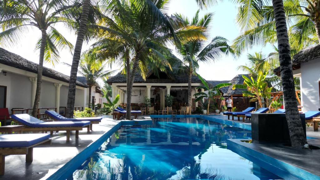 a pool at a resort with palm trees at little pompeji boutique hotel - adults only in Jambiani
