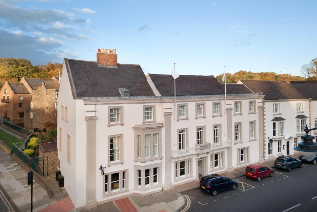 un grand bâtiment blanc avec des voitures garées devant lui dans l'établissement Delta Hotels by Marriott Durham Royal County, à Durham