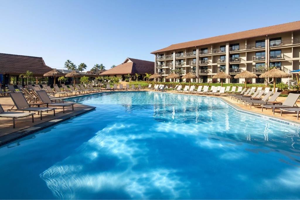 a large swimming pool with lounge chairs and a hotel at Sheraton Kauai Resort Villas in Koloa