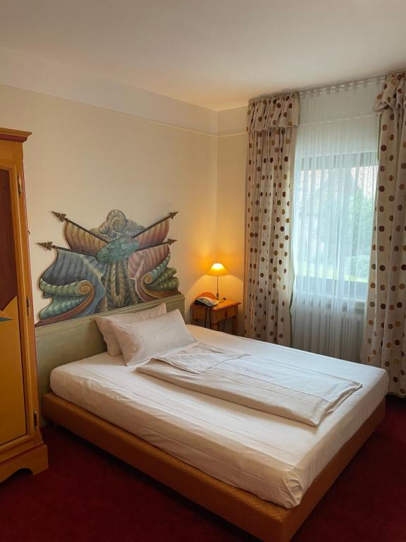 a bedroom with a bed with a painting on the wall at Hotel Schwarzwälder Hof Achern in Achern