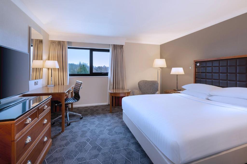 ノーサンプトンにあるDelta Hotels by Marriott Northamptonのベッド、デスク、コンピュータが備わる客室です。