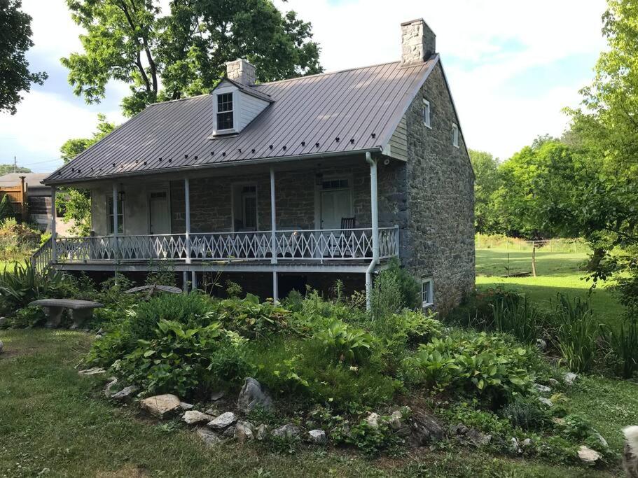 an old stone house with a porch and a balcony at Springhouse 1803 in Hagerstown
