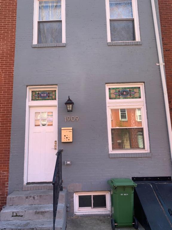 ein graues Haus mit einer weißen Tür und zwei Fenstern in der Unterkunft Beautiful master bedroom with private bathroom in Baltimore