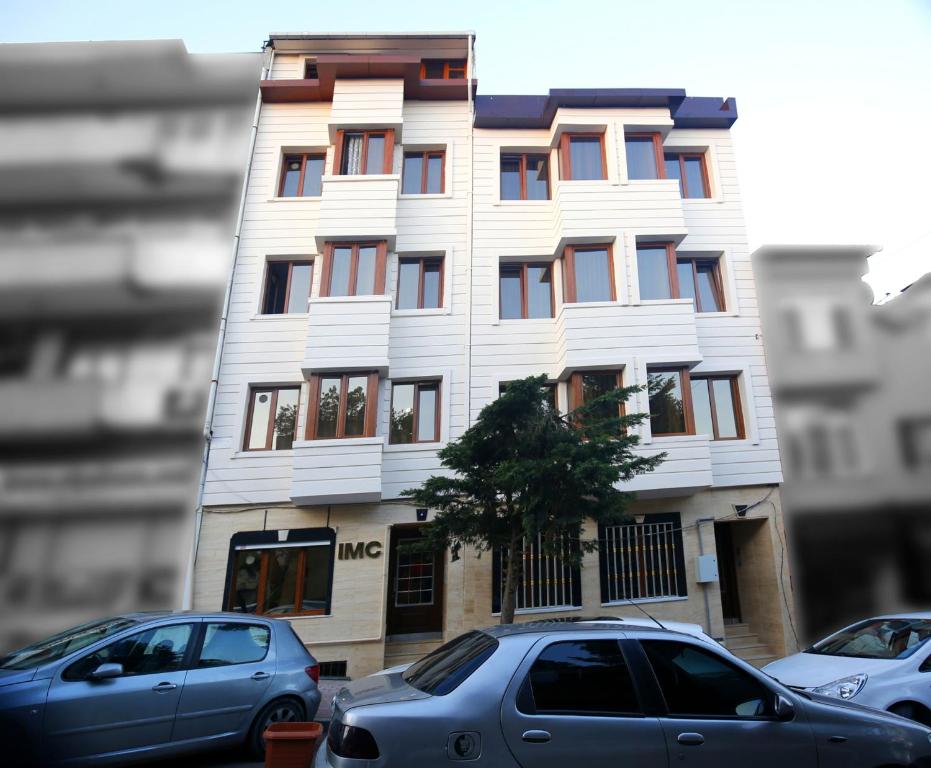 a tall white building with cars parked in front of it at IMC Fatih Apartments in Istanbul
