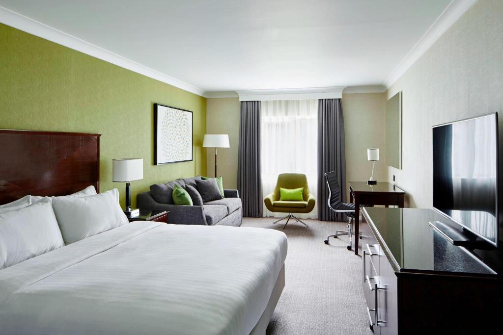 ヘイルにあるDelta Hotels by Marriott Manchester Airportのベッドとリビングルームが備わるホテルルームです。