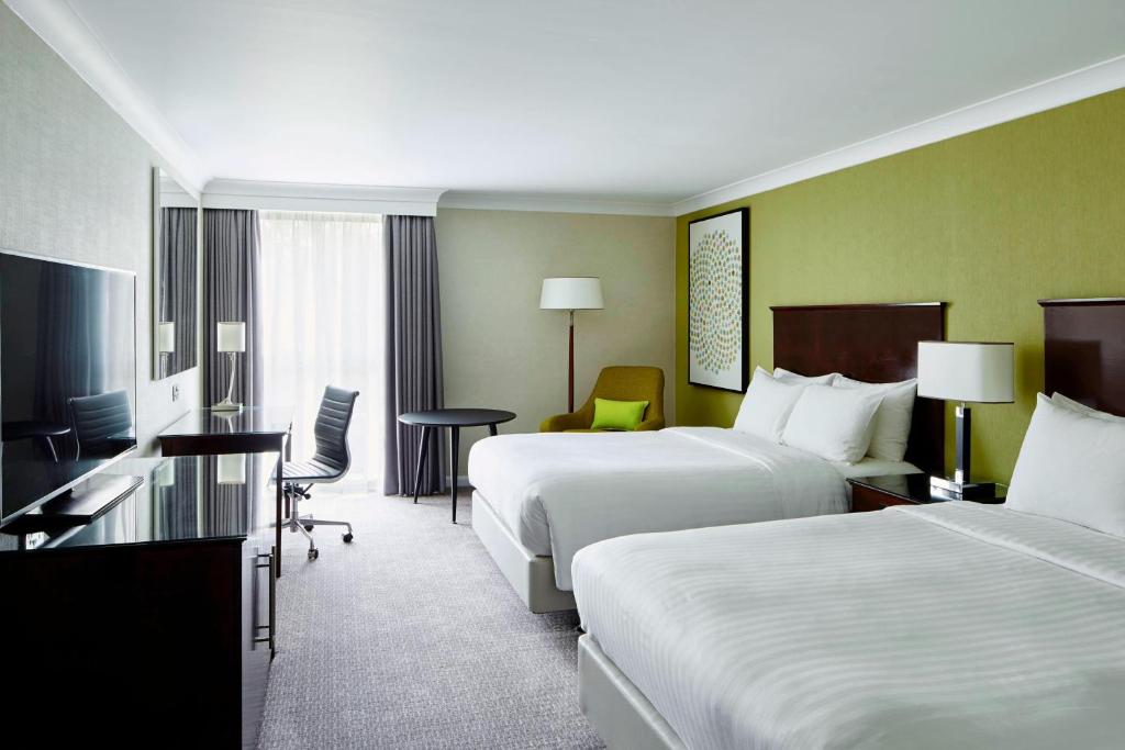 a hotel room with two beds and a desk at Delta Hotels by Marriott Manchester Airport in Hale
