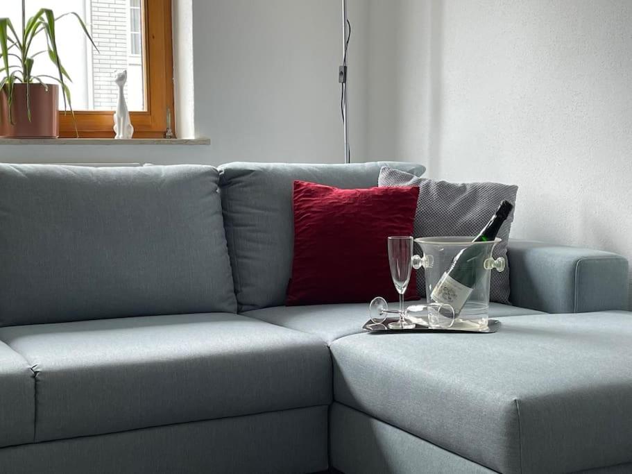 un sofá gris con una botella de vino y vasos. en Ferienwohnung Heistenbach bei Diez/Limburg, en Heistenbach