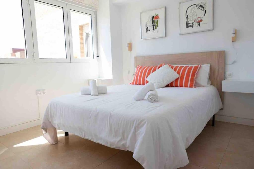 um quarto com uma grande cama branca e 2 janelas em Gran apartamento, Aire acondicionado, piscina y parking gratuito em Alicante