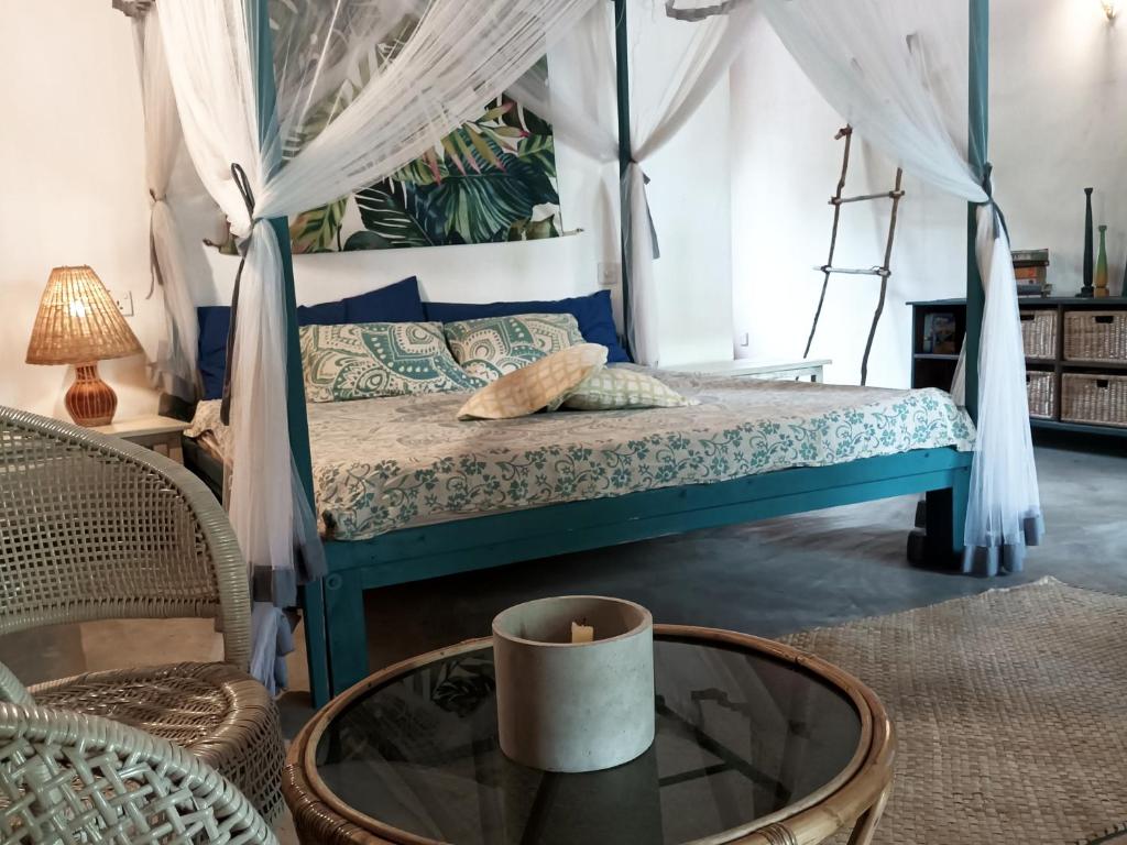 1 dormitorio con cama con dosel y mesa de cristal en The Jungle House, en Arugam Bay