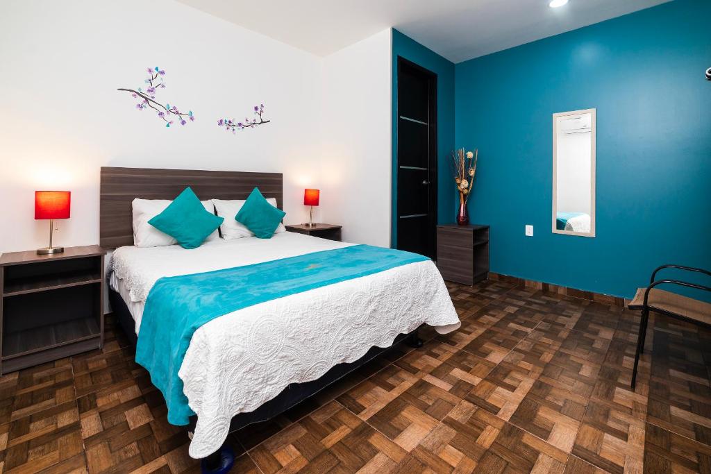 1 dormitorio con 1 cama grande y paredes azules en OYO Hotel Boutique Las Campanas, en Tlaxcala de Xicohténcatl
